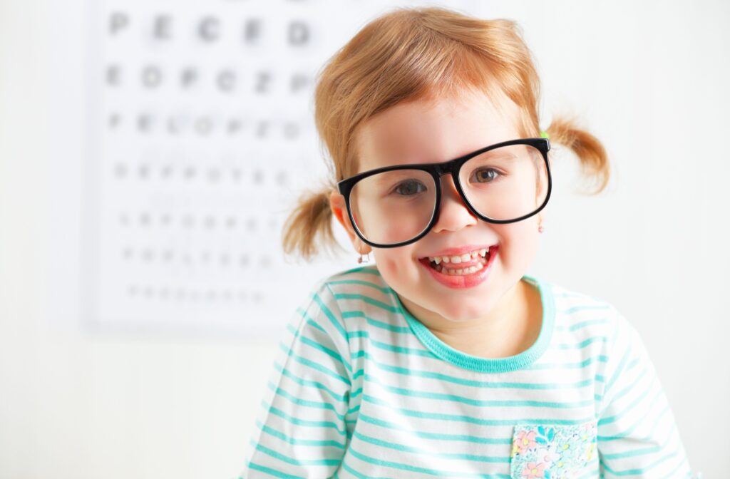 A happy, smiling child wearing large eyeglasses at the eye doctor's.