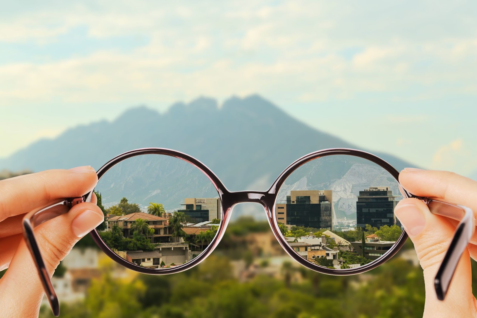 a person is holding their eye glasses which indicate they have myopia from the blurry background.