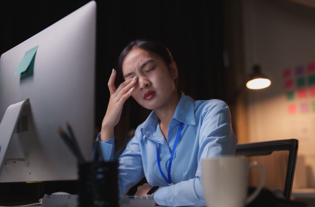 An adult rubs their tired eyes after spending hours on the computer.