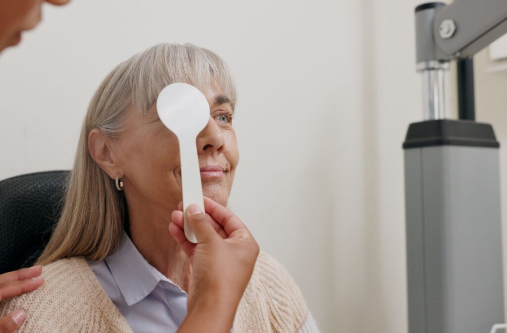 An optometrist covers a patient's eye to assess their visual sharpness during a routine eye exam.