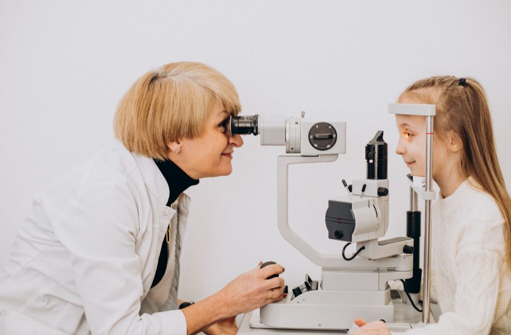 Woman in white coat looking at little girl's eyes with a slit lamp: a binocular-like device that shines a light on the eye.