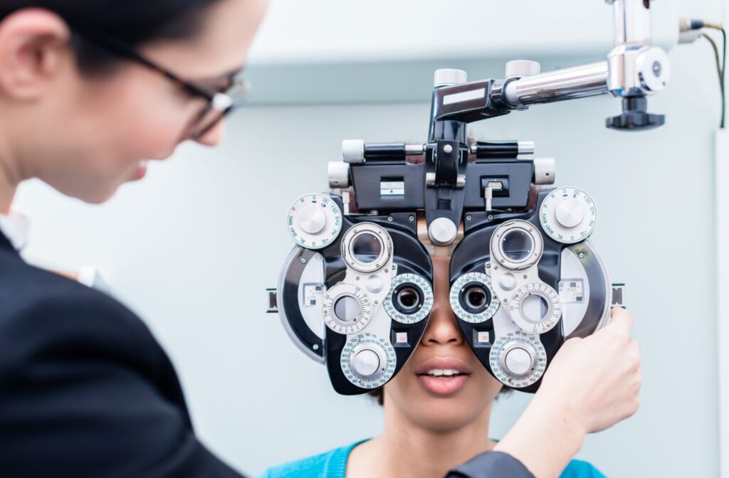 An eye doctor using a phoropter during a children's eye exam.