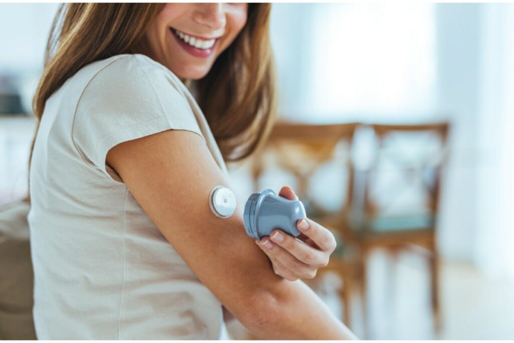 Woman with continuous glucose monitor on her arm.